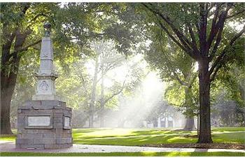 sunlight through trees near a monument